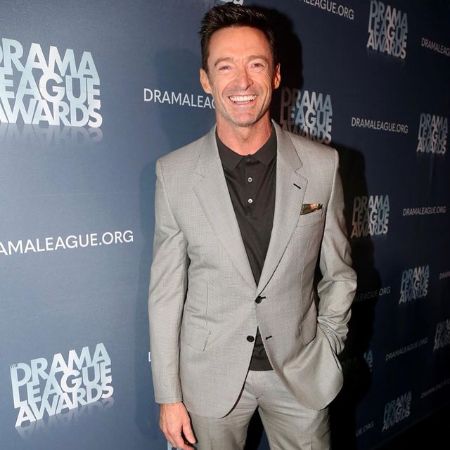 Hugh Jackman in a grey suit while posing for a picture